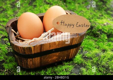 Bird eggs in wooden bucket on green grass background Stock Photo
