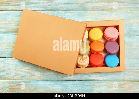 Tasty colorful macaroons in carton box on color wooden background Stock Photo