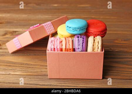 Tasty colorful macaroons in present box on rustic wooden planks background Stock Photo