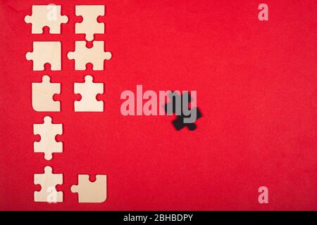 wooden puzzles of white and black color on a red background top view. stand out, leader. Stock Photo