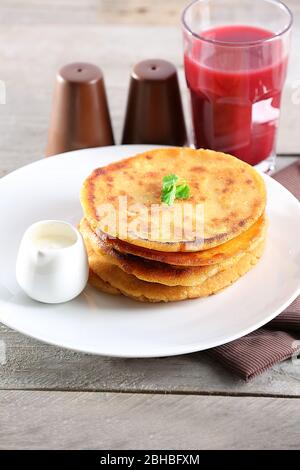 Stack of corn tortillas with stuffing and glass of juice on wooden table background Stock Photo