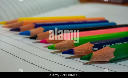 Close up of some colored pencils placed on top of the notebook Stock Photo