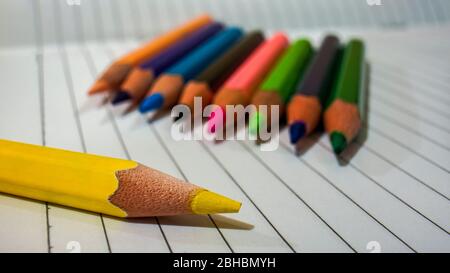 Close up of some colored pencils placed on top of the notebook Stock Photo