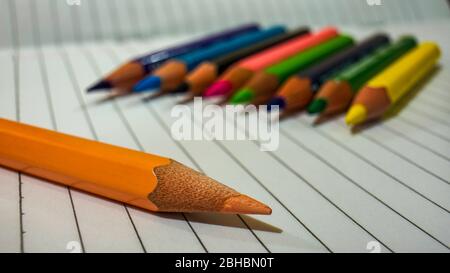 Close up of some colored pencils placed on top of the notebook Stock Photo