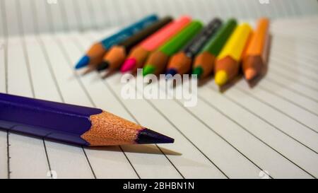 Close up of some colored pencils placed on top of the notebook Stock Photo