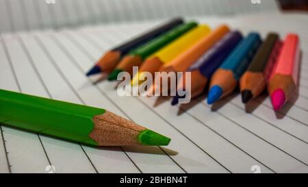 Close up of some colored pencils placed on top of the notebook Stock Photo