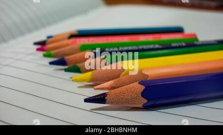 Close up of some colored pencils placed on top of the notebook