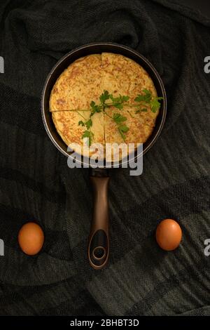 A vertical high angle closeup shot of an omelet divided into four pieces in a roaster and two eggs on the sides Stock Photo