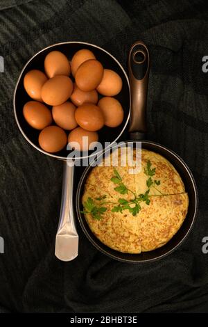 A vertical high angle closeup shot of two roasters in opposite directions with fresh eggs and an omelet divided into four parts Stock Photo
