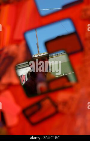 A passerby is momentarily caught in the reflections of several mirrors arranged on a brightly coloured craft market stall table in Oaxaca, Mexico. Stock Photo