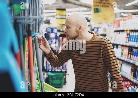 Adult bald bearded man shocked by price in hardware department of supermarket Stock Photo