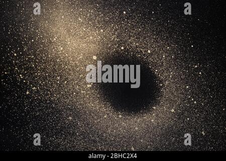 Abstract space background. Galaxy with black hole made of gold paint spray on black background. Stock Photo
