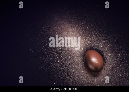 Golden egg and paint spray on black background. Abstract cosmos. Happy easter concept. Stock Photo