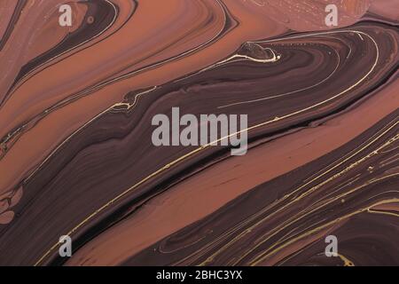 Fluid Art. Abstract Golden lines on brown waves. Marbling background or texture. Stock Photo