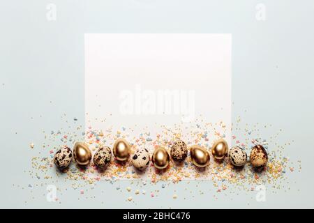 Golden eggs border and sugar sprinkles on gray pastel background. Happy easter greeting card. Stock Photo