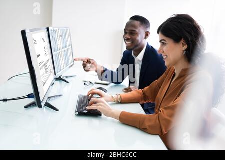 Male And Female Auditors Working On Computer With Invoice At Workplace Stock Photo