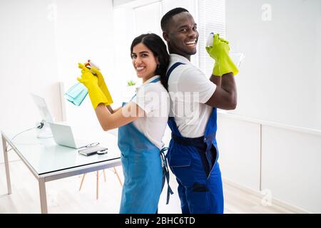 Two Janitors Standing Back To Back In Office Stock Photo