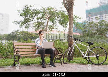 Contemporary young businessman working on his laptop in a park Stock Photo