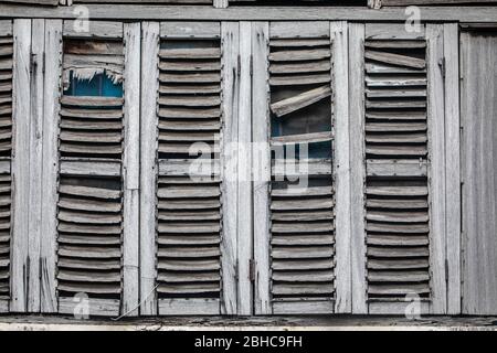 Antique windows, worn out by the weather. Gray wooden shutters. Abandoned house. Stock Photo