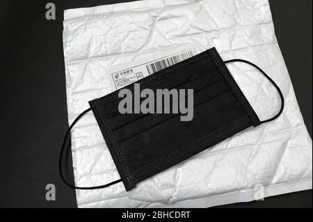 Fuji City, Shizuoka Prefecture, Japan - March 22, 2020: Black surgical mask on top of bubble wrap padded envelope with China Post label. Stock Photo