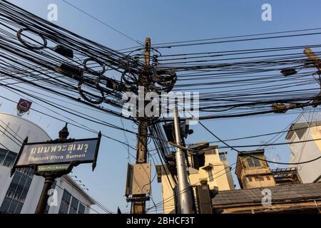 Bangkok, Thailand - March 2nd, 2020: An abundance of electricity cables stretched between poles over a Bangkok street. Stock Photo