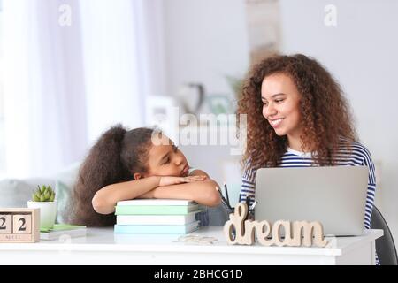 African-American mother and bored little schoolgirl at home Stock Photo