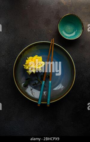 Table setting with yellow roses and cutlery on rustic table with copy space Stock Photo