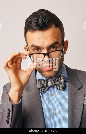 guy wearing glasses looking away and leaning on grey wall. Portrait of young businessman with eyeglasses thinking about his carrer with copy space Stock Photo