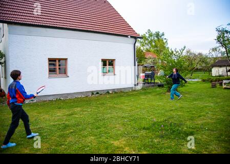 Mother and her son playing badminton in their backyard during the coronavirus lockdown measures Stock Photo
