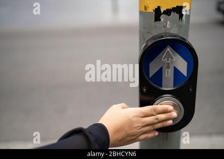Traffic control. woman presses a finger on the button in front of a traffic light to safely cross a road. Close up. Stock Photo