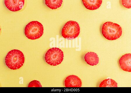 ripe, fresh, natural red cut strawberries pattern, a healthy spring and summer fruit, on yellow background Stock Photo