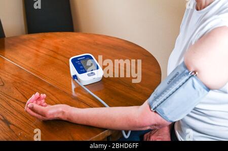 Middle aged woman using an Omron Blood Pressure testing monitor at home  Photograph taken by Simon Dack Stock Photo