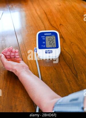 Middle aged woman using an Omron Blood Pressure testing monitor at home  Photograph taken by Simon Dack Stock Photo