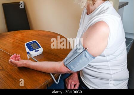 Middle aged woman using an Omron Blood Pressure testing monitor at home  Photograph taken by Simon Dack Stock Photo