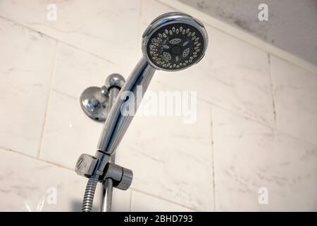 Dirty chrome shower head with limescale that should be cleaned and mold on tiles and ceiling. Calcified shower due to hard water. Calcium mineral buil Stock Photo