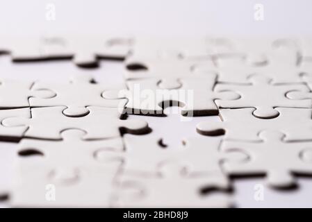 Close up on blank, white jigsaw puzzle pieces. One piece is laking Stock Photo