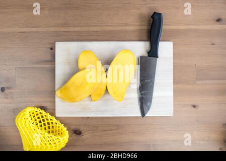 A ripe yellow fresh mango sliced on a chopping board. Stock Photo