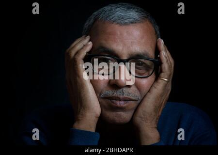 Close up portrait of thinking senior man on black background Stock Photo