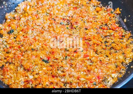 Cooking different small cut vegetables in a paella to prepare a sofrito for a paella. Stock Photo