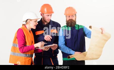 Men and woman in helmets, architects on busy faces looks at drawing, plan, blueprint, project, white background. Team of builder, engineer, architect arguing about project. Misunderstanding concept. Stock Photo