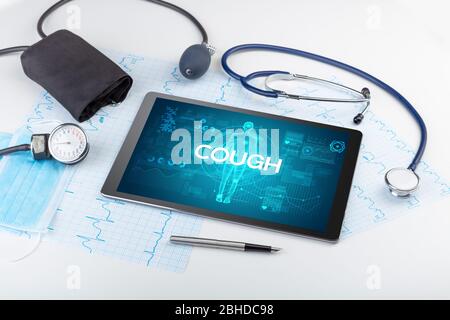 Tablet pc and doctor tools with COUGH inscription, coronavirus concept Stock Photo