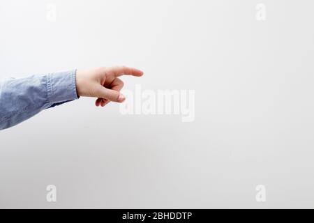 Man's hand in a blue shirt touching or pointing to something on white wall background. Close up. Copy space Stock Photo