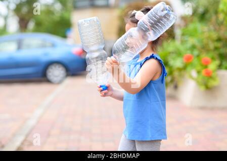 Little girl holding plastic water bottles for recycling. Concept plastic free world, the future for our children. Zero waste. Stock Photo