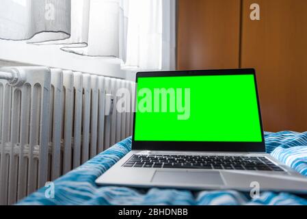 Laptop used to work from home in the bedroom, green screen on laptop blurred in the room, smart working Stock Photo
