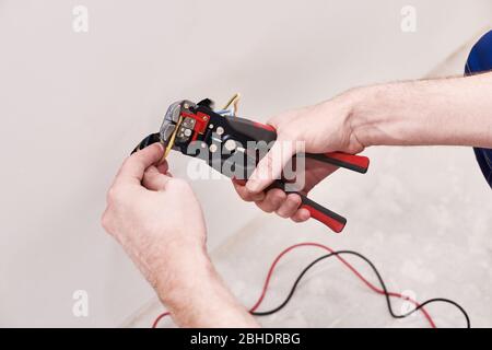 Hands man make connection terminal wire, hold crimping pliers. Design background. Professional materials. Electric work. Male hobby Stock Photo