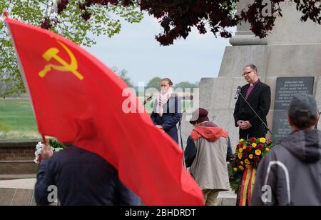 Torgau, Germany. 25th Apr, 2020. Romina Barth (CDU), Lord Mayor of Torgau, and Johann Schneider, Regional Bishop Halle-Wittenberg of the Protestant Church in Central Germany, stand at the Monument of Encounter, with the flag of the Soviet Union waving in the foreground. On the occasion of the 75th anniversary of the meeting of American and Soviet soldiers on April 25, 1945 - the so-called Elbe Day - a commemoration ceremony was held, which took place in a small circle because of the corona pandemic and was transmitted online. Credit: Sebastian Willnow/dpa-Zentralbild/dpa/Alamy Live News Stock Photo