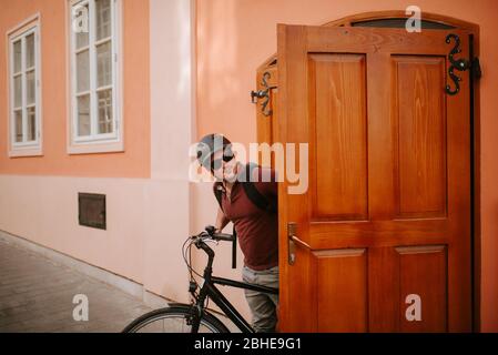 Handsome young caucasian cyclist standing in front of house Stock Photo