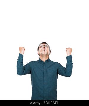 Thankful and pleased businessman keeps fists raised up, looking contented upwards isolated on white background with copy space. Grateful guy winner ce Stock Photo