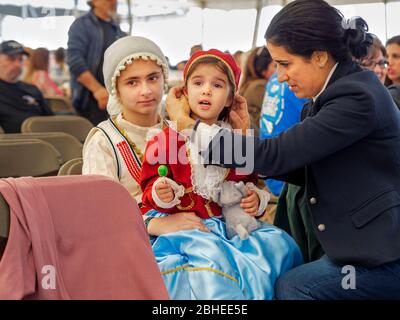 A woman adjusts the bonnet of the younger of two girls dressed in Greek costume at the 2019 Greek Festival in Corpus Christi, Texas USA. Stock Photo