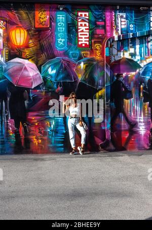 Portrait of a young woman posing next to a colourful decorative graffiti, Wynwood Walls, Miami, Florida, USA. Stock Photo
